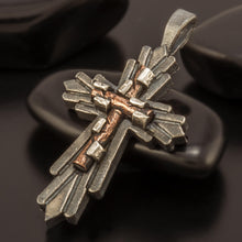 Side view of the mixed metal cross pendant showing silver and copper layers.