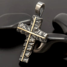 Detailed artisan hammered texture on a rustic silver cross with a smooth gold cross accent.