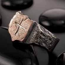 Handmade Viking-style cross ring RS-1424 displayed on dark pebbles, showcasing its ancient and rugged aesthetic.