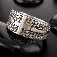 Artisan mixed metal cross ring RS-1423 placed on dark pebbles, displaying its heavy, rugged aesthetic and master-forged metalwork.